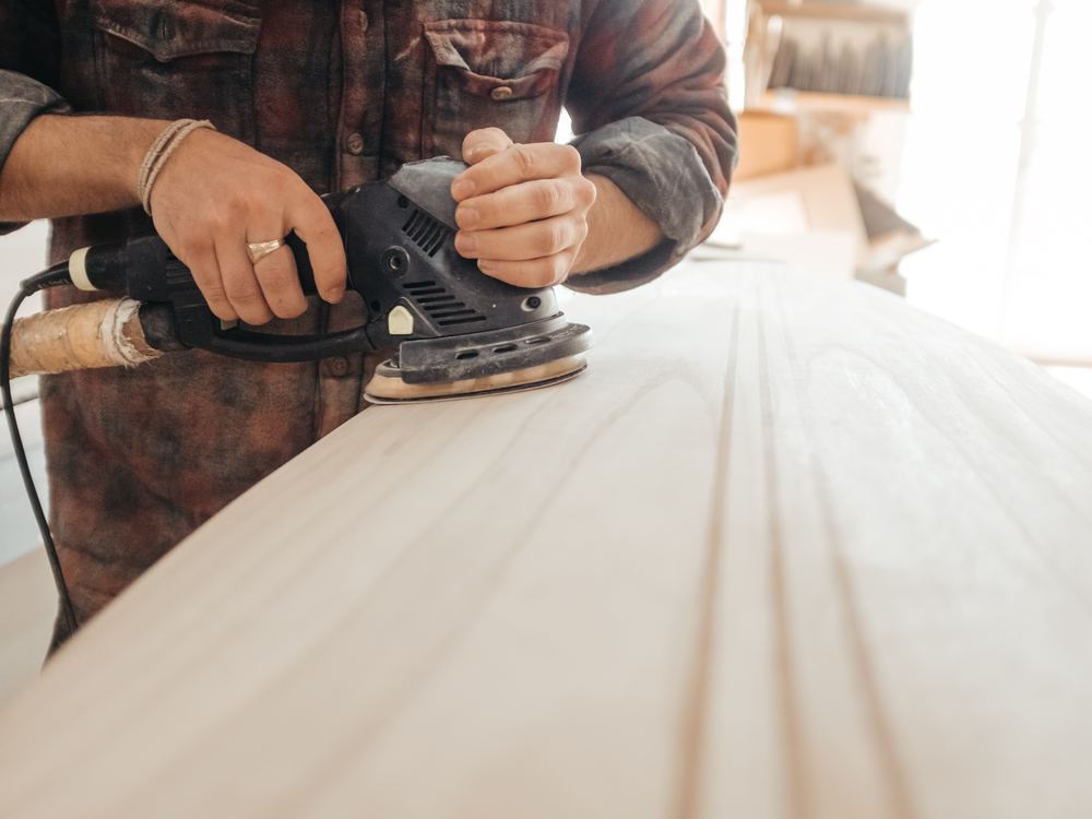 Timmerman schuurt een houten plank in de werkplaats
